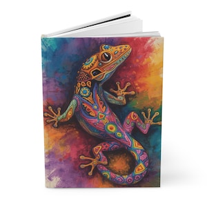 May include: A hardcover journal featuring a colorful, artistic illustration of a gecko. The gecko is adorned with intricate patterns in shades of orange, blue, pink, and green against a vibrant, multi-colored background.
