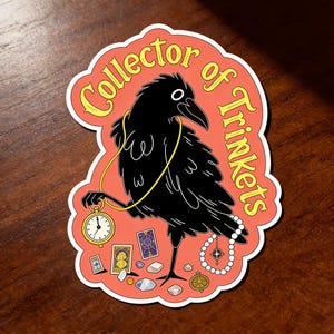 May include: A sticker featuring a black crow with a gold necklace and a pocket watch. The crow is holding a pocket watch and surrounded by trinkets, with the words "Collector of Trinkets" in yellow text on a peach background.