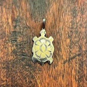 Peut inclure: Un pendentif en argent en forme de tortue avec un motif détaillé sur sa carapace.