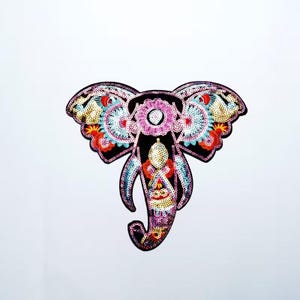 May include: A decorative elephant patch with intricate sequin and beadwork. The elephant is black with colorful floral and geometric patterns in pink, blue, red, and gold. The patch has a detailed, embroidered design.