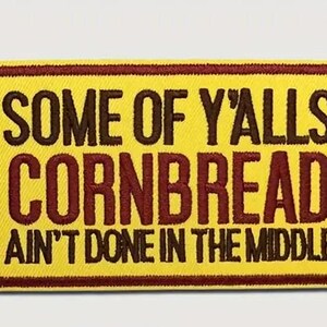 May include: Yellow and brown embroidered patch with the text "Some of Y'alls Cornbread Ain't Done in the Middle."