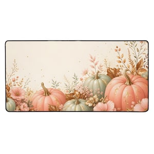 Puede incluir: Una alfombrilla de escritorio rectangular con fondo color crema que presenta una disposición horizontal de calabazas en rosa pastel y verde salvia, follaje otoñal delicado y pequeños detalles florales, bordeada por un fino marco negro.