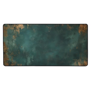 May include: A rectangular desk mat featuring a dark teal and copper-toned distressed, mottled texture across the surface. The mat has a solid black stitched border that frames the entire rectangular shape, providing a clean, finished edge.