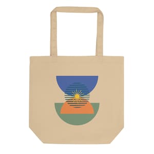 May include: Beige tote bag with a geometric design. The design features a blue semi-circle at the top, a striped circle with a sun in the middle, and orange and green semi-circles at the bottom. The bag has a rectangular shape and two beige handles.