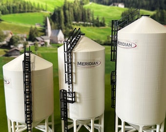 Könnte beinhalten: Drei weiße Getreidesilos mit schwarzen Leitern und dem Wort "MERIDIAN" auf der Seite. Die Silos stehen auf einer grünen Fläche mit einer Visitenkarte, auf der "FARMER BILLY CUSTOM MADE TOYS" steht.