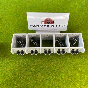 May include: A set of five white plastic stalls with black and white cows inside. The stalls are labeled "Farmer Billy - Custom Made Toys".
