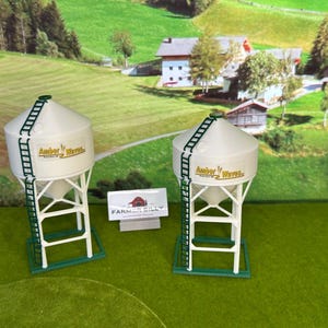 May include: Two white grain silos with green ladders and the text "Amber Werle" on the side. The silos are on a green grassy surface.