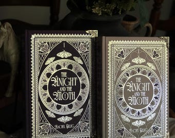 Puede incluir: Dos libros de tapa dura titulados "The Knight and the Moth" con diseños ornamentados en pan de oro. Uno es morado oscuro, el otro gris claro. Las portadas presentan polillas y bordes decorativos. La autora es "Rachel Gillig".