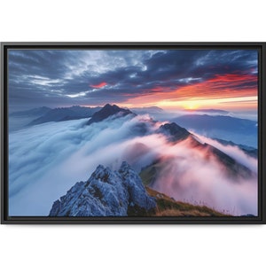 May include: A panoramic view of a mountain range with a layer of clouds at the base of the peaks. The sky is a vibrant mix of pink, orange, and purple hues, suggesting a sunrise or sunset.