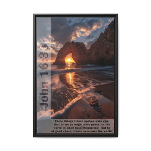May include: A framed print with a sunset scene of a rocky archway over a beach. The print includes the Bible verse John 16:33, "These things I have spoken unto you, that in me ye might have peace. In the world ye shall have tribulation: but be of good cheer; I have overcome the world."