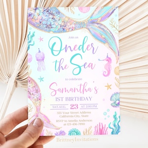 May include: A light blue and pink invitation with a mermaid tail and the text "Join us Oneder the Sea to celebrate Samantha's 1st Birthday SAT AUG 23 AT 2:00 PM 555 Your Street Address California City, State RSVP to Amelia Anderson at 123-456-7890 Brittney Invitations".
