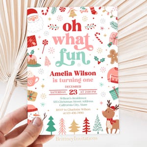 May include: A Christmas-themed first birthday party invitation featuring a red and white Santa Claus, a gingerbread man, a snowman, and a reindeer. The invitation reads "oh what fun Amelia Wilson is turning one" and includes the date, time, and location of the party.