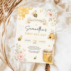 May include: A cream-coloured birthday invitation card featuring watercolour illustrations of bees, a honeycomb, a beehive, and pink flowers. The text reads: JOIN US TO CELEBRATE Samantha's FIRST BEE-DAY, SATURDAY 28 MAY AT 2:00 PM, and event details.
