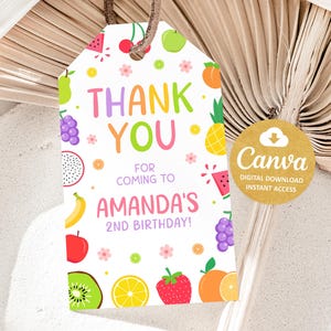 Puede incluir: Una colorida etiqueta de recuerdo de fiesta de cumpleaños con el texto "THANK YOU" en colores arcoíris, rodeada de ilustraciones de frutas. La etiqueta dice "FOR COMING TO AMANDA'S 2ND BIRTHDAY!" e incluye un logotipo de Canva.