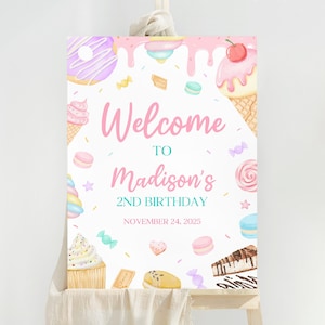 May include: A pink and blue welcome sign with a candy theme for a 2nd birthday party. The sign says "Welcome to Madison's 2nd Birthday, November 24, 2025".