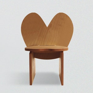 May include: A wooden chair shaped like a heart. The chair is made of light brown wood and has a simple design.