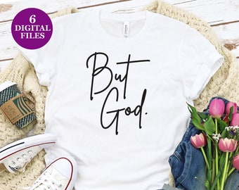 May include: White t-shirt with the text "But God" written in black cursive script. The shirt is laid flat on a wooden surface with a pair of white trainers, a pair of blue jeans, and a bouquet of pink flowers.