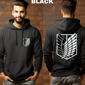May include: Black hooded sweatshirt with a white graphic of the Attack on Titan logo on the front and back. The logo features a pair of wings with a shield in the center.