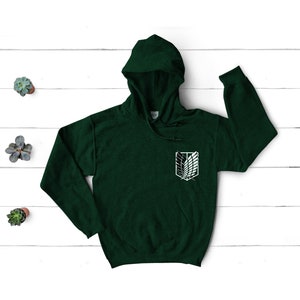 May include: A dark green hooded sweatshirt with a white graphic of the Attack on Titan symbol on the left chest.