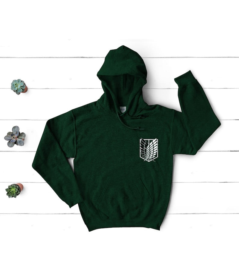 May include: A dark green hooded sweatshirt with a white graphic of the Attack on Titan symbol on the left chest.