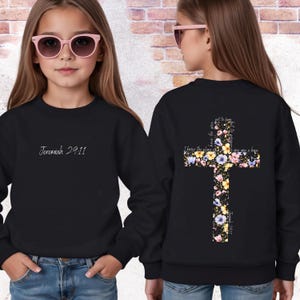 May include: Black sweatshirt with the text "Jeremiah 29:11" on the front. The back of the sweatshirt features a floral cross design with the text "I know the plans I have for you, plans to give you hope".