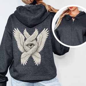 May include: Dark gray zip-up hoodie featuring a detailed illustration of an eye within intertwined wings on the back. The design is in a vintage style with a neutral color palette. The hoodie has a drawstring hood and a full-length zipper.