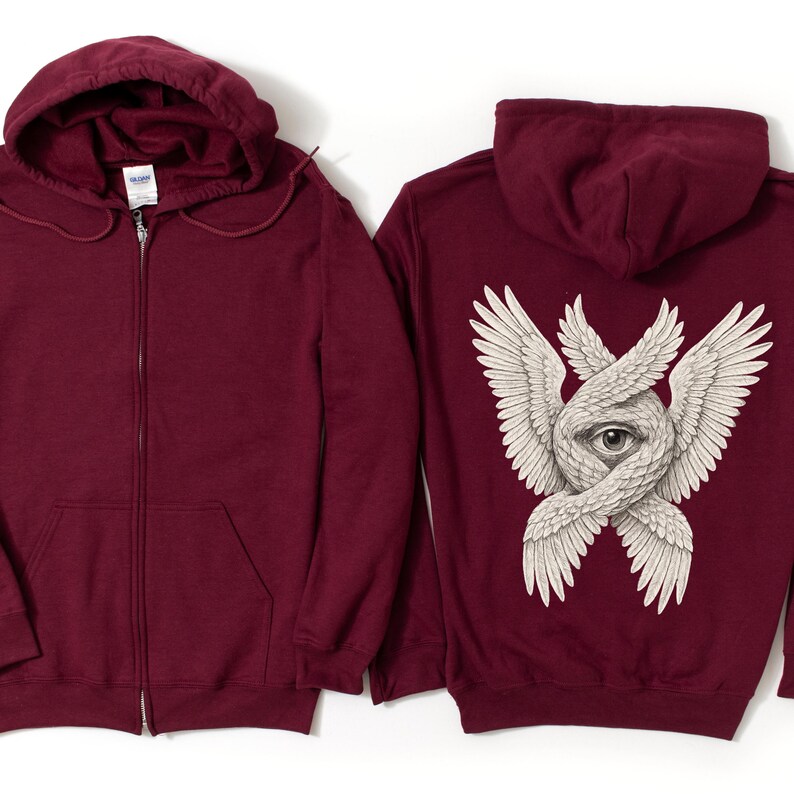 May include: A maroon zip-up hoodie with a hood and front pockets. The back of the hoodie features a detailed graphic of an eye surrounded by intertwined wings in white. The hoodie is made of a soft material.