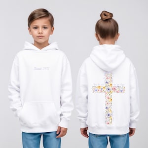 May include: White hoodie with a front pocket and a hood. The front of the hoodie has the text "Jeremiah 29:11" in a script font. The back features a cross design filled with colorful flowers and the text "I know the plans I have for you, plans to give you a hope".