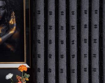 Può includere: Tende grigie con un motivo testurizzato nero. Le tende sono appese davanti a un muro nero.