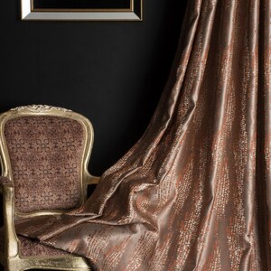 Op de afbeelding: Een luxueus interieur met een goudomrand kunstwerk, een vintage stoel met sierlijke details en vloeiende bruine gordijnen. De gordijnen hebben een textuurpatroon, wat diepte en elegantie toevoegt aan de kamerinrichting.