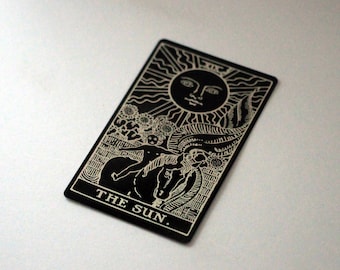 Puede incluir: Carta de tarot en blanco y negro con la imagen del sol y una persona montando a caballo. La carta dice "THE SUN."