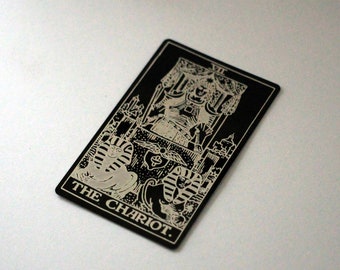 Puede incluir: Carta de tarot en blanco y negro con la imagen de un carro y el texto "THE CHARIOT" en la parte inferior.