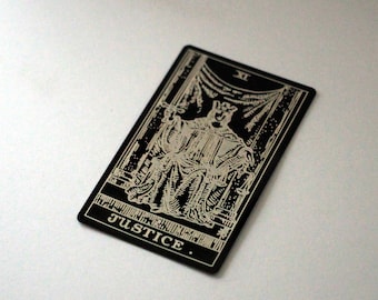 Puede incluir: Carta de tarot en blanco y negro con el número romano XI y la palabra "JUSTICE" impresa en la parte inferior. La carta representa una figura con una corona que sostiene una espada y una balanza.