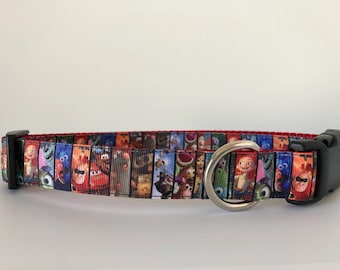 May include: A red, black, and white dog collar with a colorful print of characters from the movie "Monsters, Inc." and "Toy Story".