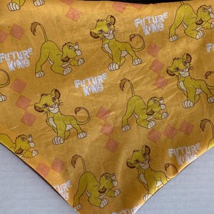 May include: Yellow bandana with a repeating pattern of lion cubs and the text "Future King".