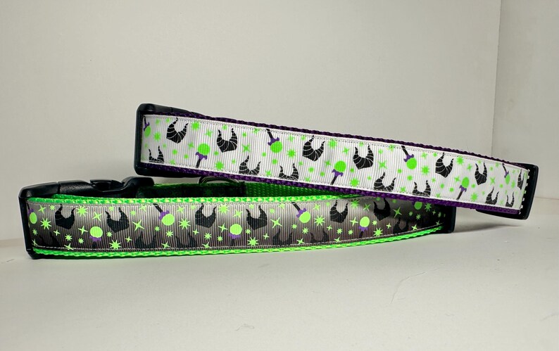 Op de afbeelding: Twee hondenhalsbanden met een groen-wit patroon met een silhouet van Maleficent's hoorns en een groene appel. De bovenste halsband heeft een paarse achterkant en de onderste halsband heeft een zwarte achterkant.