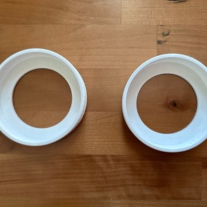 May include: Two white plastic rings, possibly for a craft project or to hold something in place.