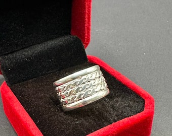 May include: A silver ring with a braided design, displayed in a red velvet ring box.