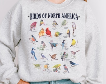 May include: A gray sweatshirt with a graphic print of various birds of North America. The text "*BIRDS OF NORTH AMERICA*" is printed in navy blue above the birds.
