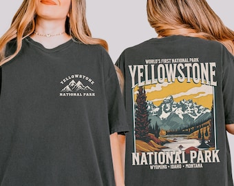 May include: A black t-shirt with a vintage-style graphic of Yellowstone National Park. The front of the shirt has a small logo with the words "Yellowstone National Park". The back of the shirt has a larger graphic with the words "World's First National Park Yellowstone National Park Wyoming - Idaho - Montana".