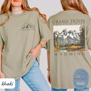 May include: Khaki t-shirt with a graphic of the Grand Teton National Park mountains and the text "Grand Teton National Park Wyoming".