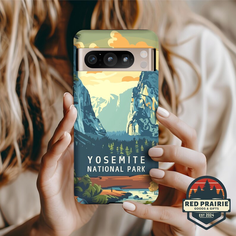 May include: A phone case featuring a landscape design of Yosemite National Park. The case has a colorful illustration of mountains, trees, and a lake. The text "YOSEMITE NATIONAL PARK" is printed on the case. The case also has the logo of "RED PRAIRIE GOODS & GIFTS EST 2024".
