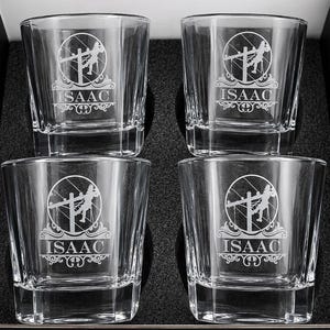 Four personalized Lineman rocks glasses engraved with the name Isaac, arranged in a black foam gift box.