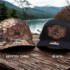 May include: Two trucker hats with leather patches. One hat is Kryptek camo with a deer silhouette, the other is black with a turkey design. Both hats have mesh backs and the text "KRYPTEK CAMO" and "BLACK" are visible.