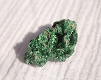 以下が含まれることがあります： ざらざらとした質感の緑色の孔雀石の結晶。結晶は自然で土のような外観をしています。