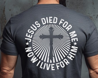 Puede incluir: Camiseta gris oscuro jaspeada con un gráfico blanco en la espalda. El gráfico presenta una cruz con un diseño de rayos de sol y el texto "Jesus Died For Me, Now I Live For Him".