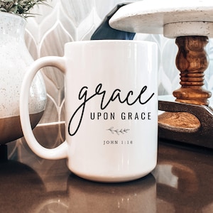 May include: White ceramic coffee mug with black text that reads "grace upon grace John 1:16".