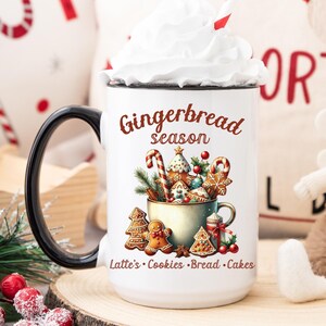 May include: White mug with a black handle, filled with whipped cream and a red and white striped straw. The mug features a "Gingerbread season" design with gingerbread cookies and text: Lattes, Cookies, Bread, Cakes. Christmas theme.
