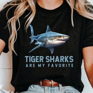 May include: A black t-shirt with a blue tiger shark graphic and the text "Tiger Sharks Are My Favorite".