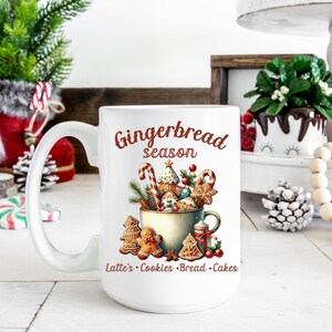 May include: White ceramic mug with a festive "Gingerbread season" design. The mug features a watercolor illustration of gingerbread cookies, candy canes, and greenery. Text at the bottom reads "Latte's Cookies Bread Cakes".